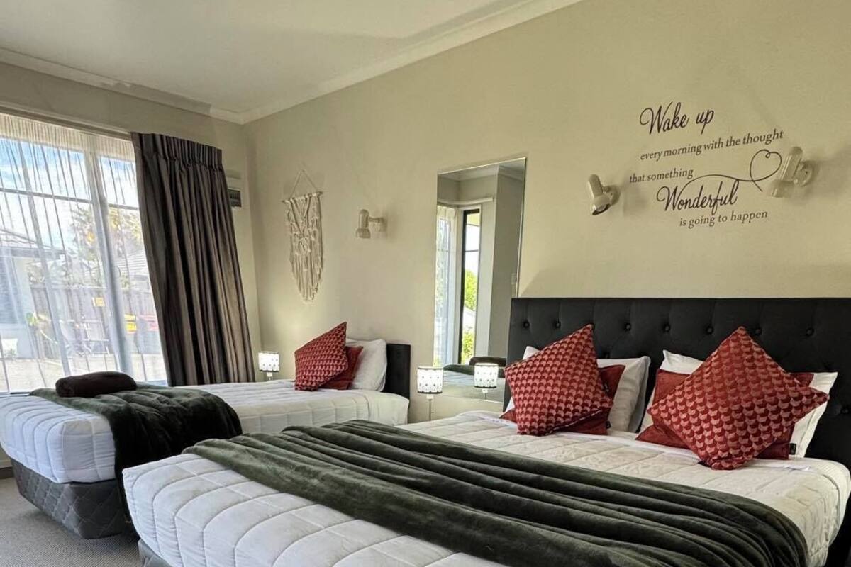 A hotel room with two beds, a large mirror, and a motivational quote on the wall.