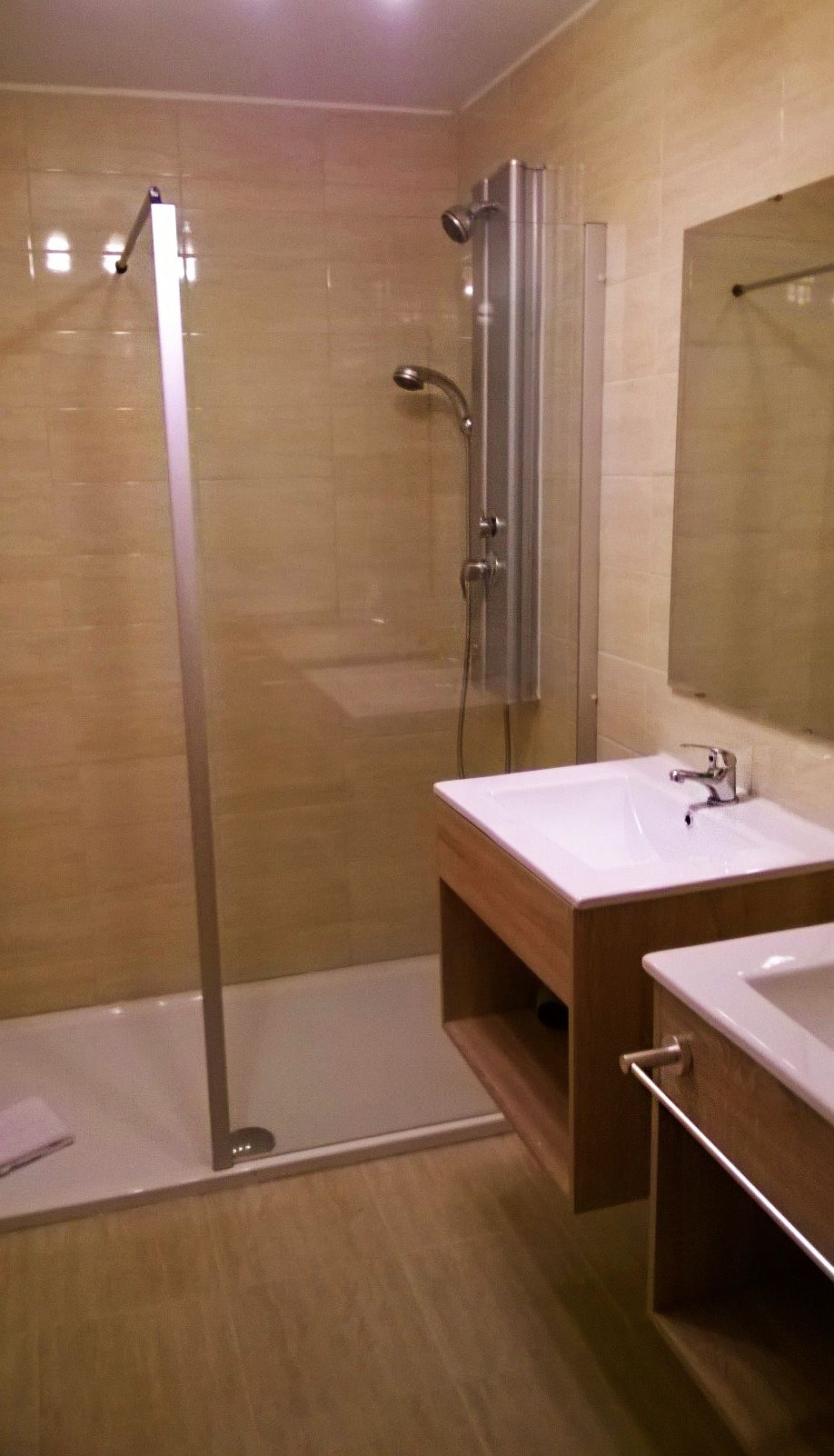 A modern bathroom with a glass-enclosed shower, a wooden vanity with a white sink, and a mirror above the sink.