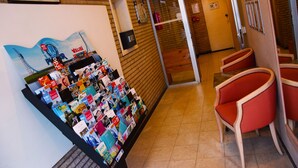 A reception area with a 'Welcome to Your Home' sign, a display of magazines, and red chairs. - City Apartments Antwerp (Antwerp)