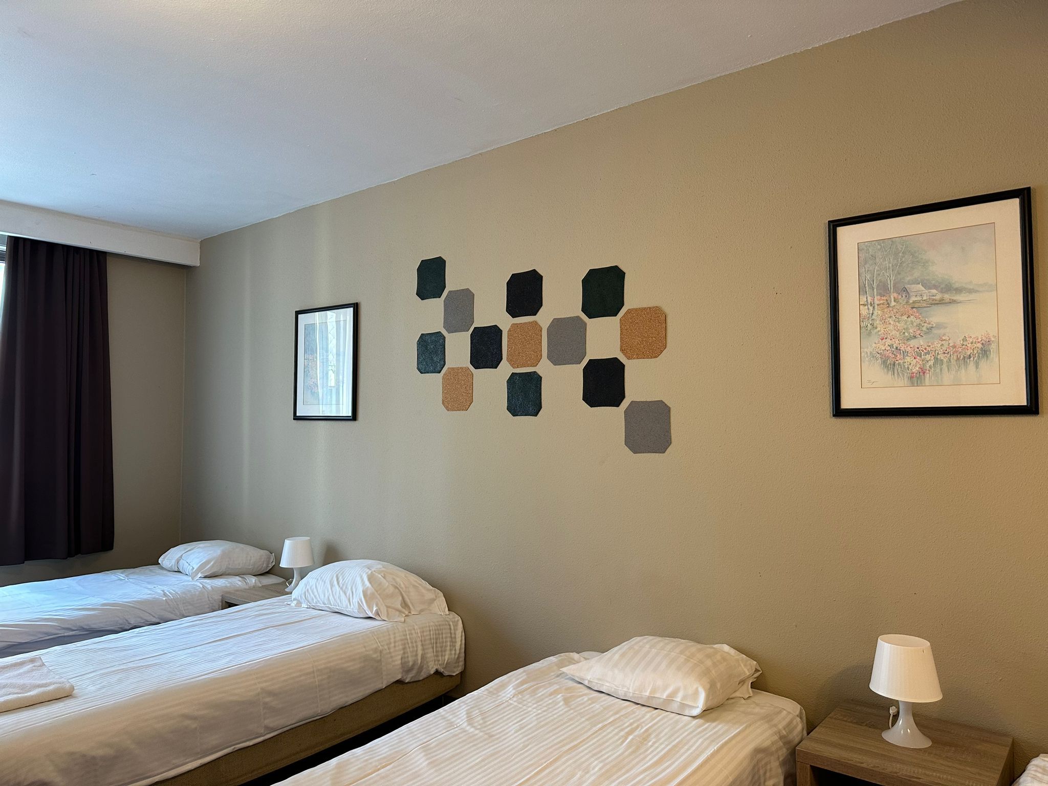 Habitación de hotel con dos camas, un cuadro y un adorno en la pared.