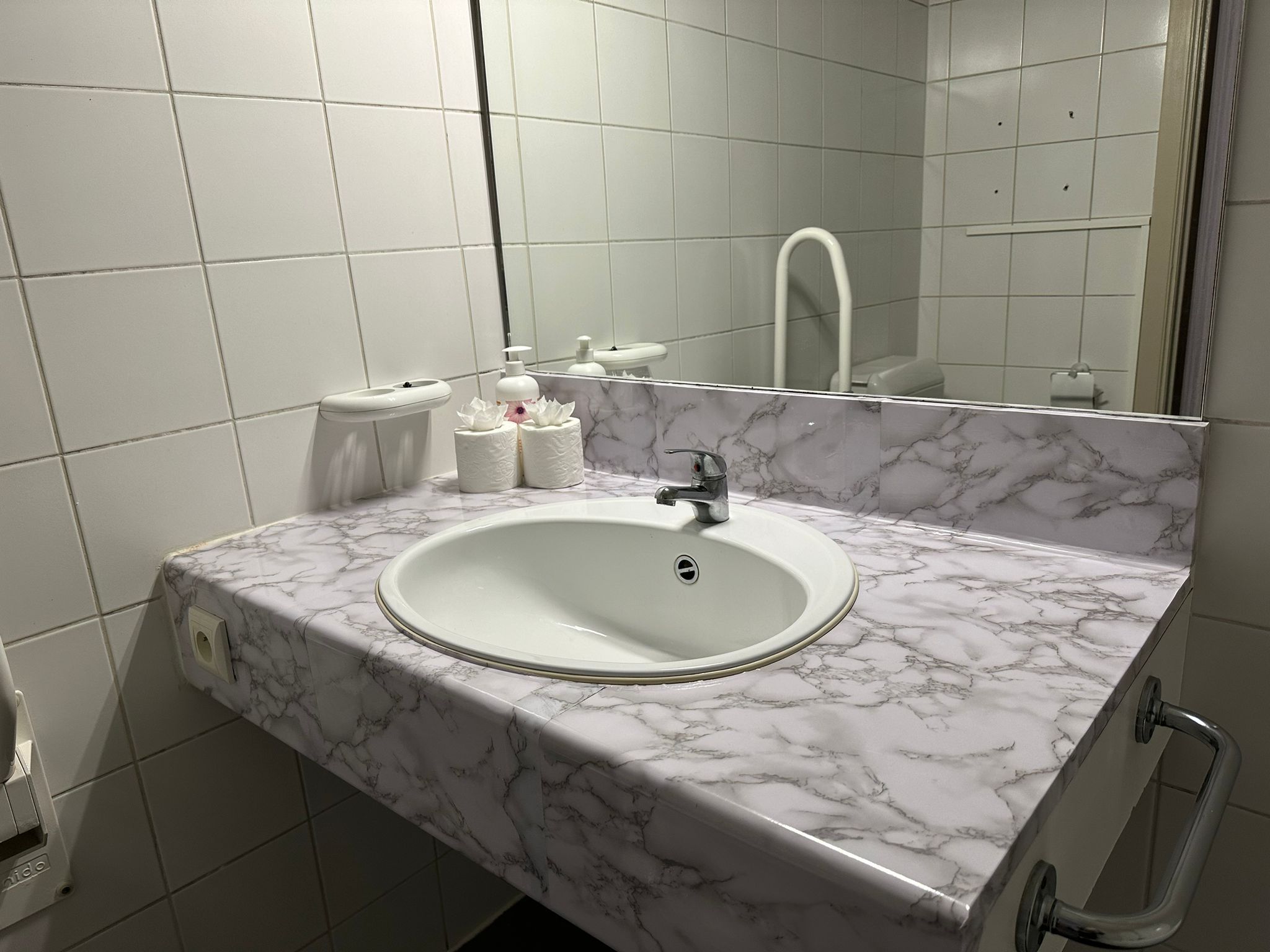 A bathroom with a marble sink, a mirror, and a toilet.