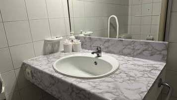 A bathroom with a marble sink, a mirror, and a toilet.