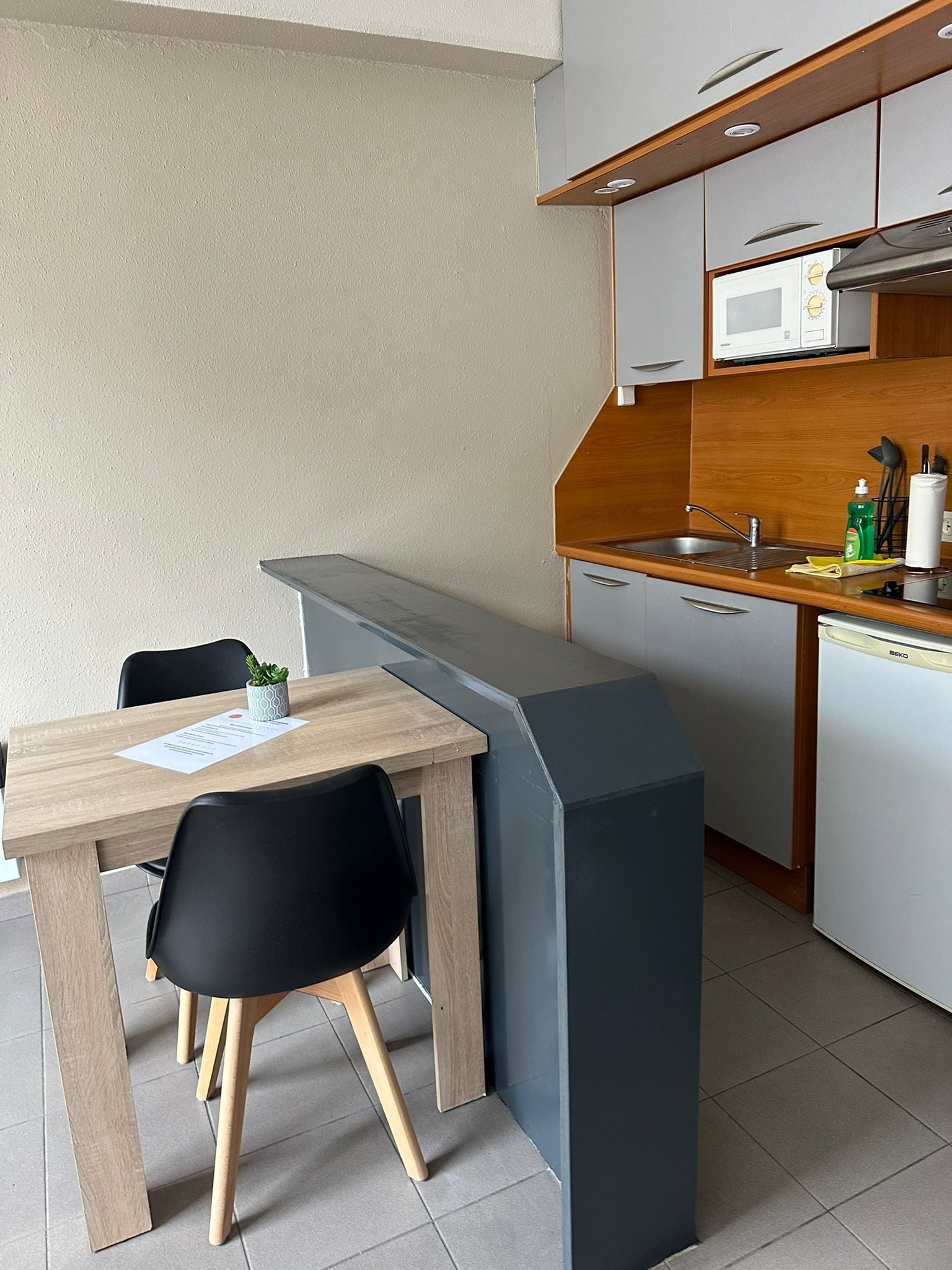 A compact kitchenette with a microwave, sink, and storage cabinets.