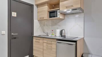A compact kitchen with a microwave, kettle, and dishwasher.