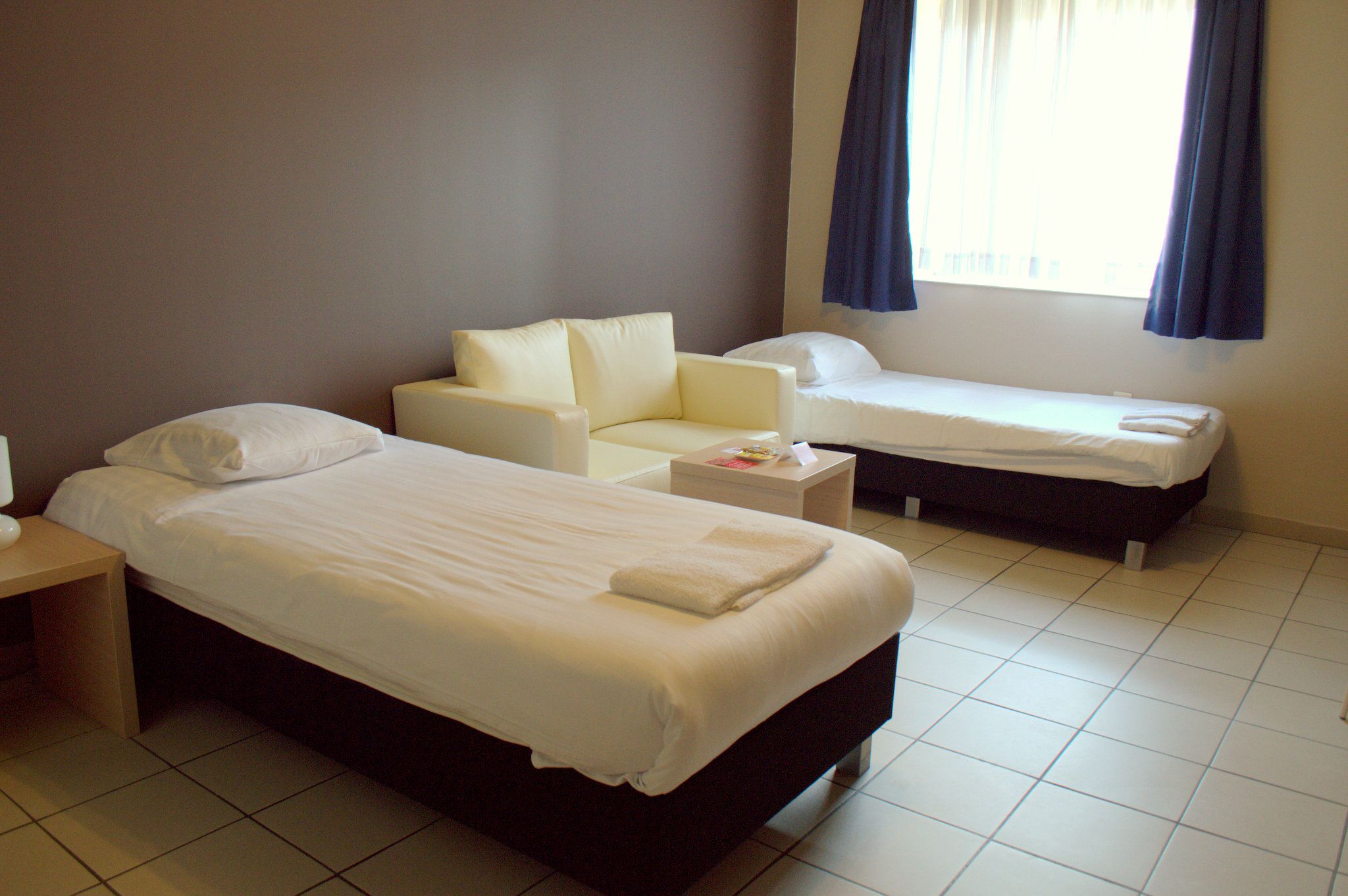 Una camera d'albergo con due letti, un divano e un tavolino.