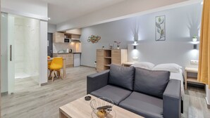 A modern living room with a grey sofa, a wooden coffee table, and a kitchen area with a microwave and sink. - Budget Flats Leuven (Leuven)