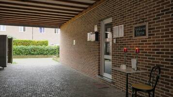 Un bâtiment en briques avec une enseigne accueillante, une table avec des bougies et une chaise.
