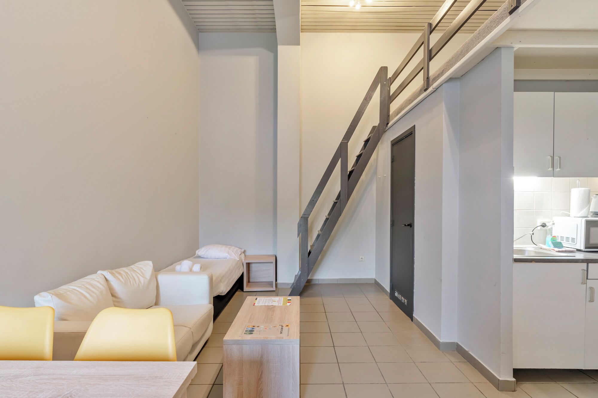Una sala de estar moderna con un sofá, una mesa de centro y una escalera que conduce a una zona de cocina.