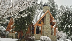A stone cabin with a steeply pitched roof, wooden beams, and a chimney. - Tillka, Casas de Montaña (Villa La Angostura)