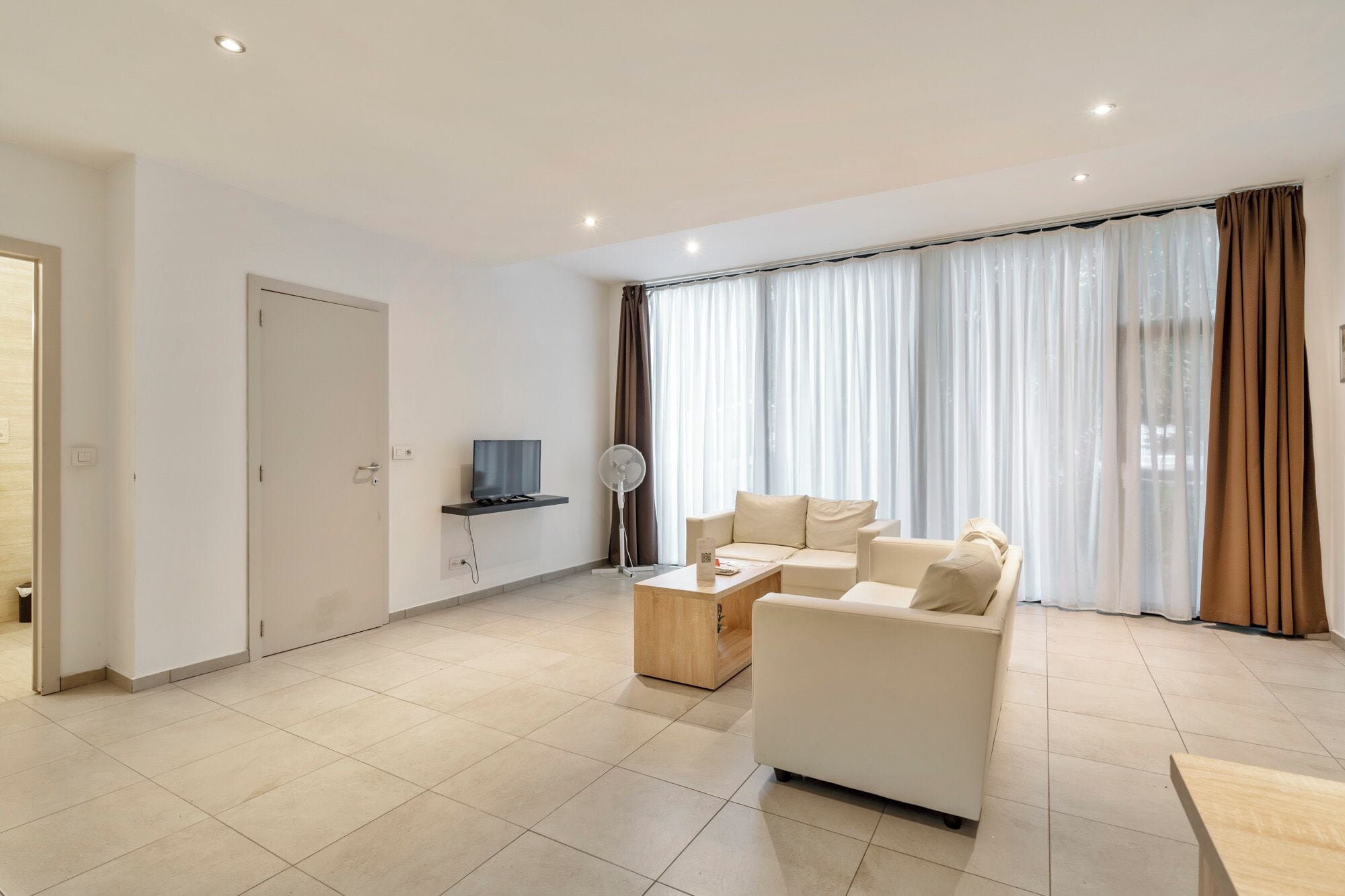 Una sala moderna con sofá, mesa de centro y televisor sobre una estantería.