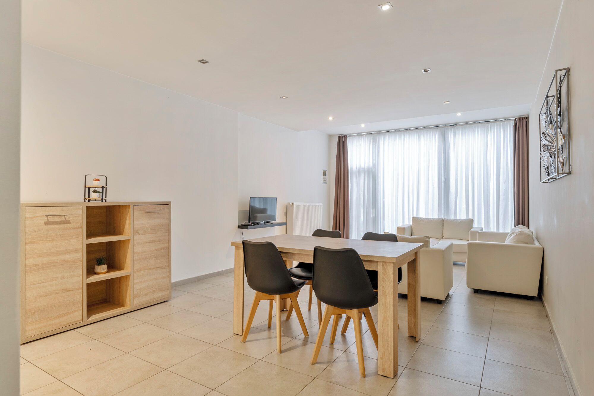 Ein modernes Wohnzimmer mit Essbereich, Fernseher und Sofa.