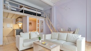 Una sala de estar moderna y bien iluminada con un sofá, una mesa de centro y una cama litera con escalera.