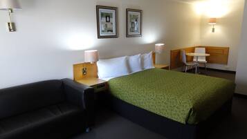 Een hotelkamer met een bed, een stoel, een bureau en twee wandlampen.