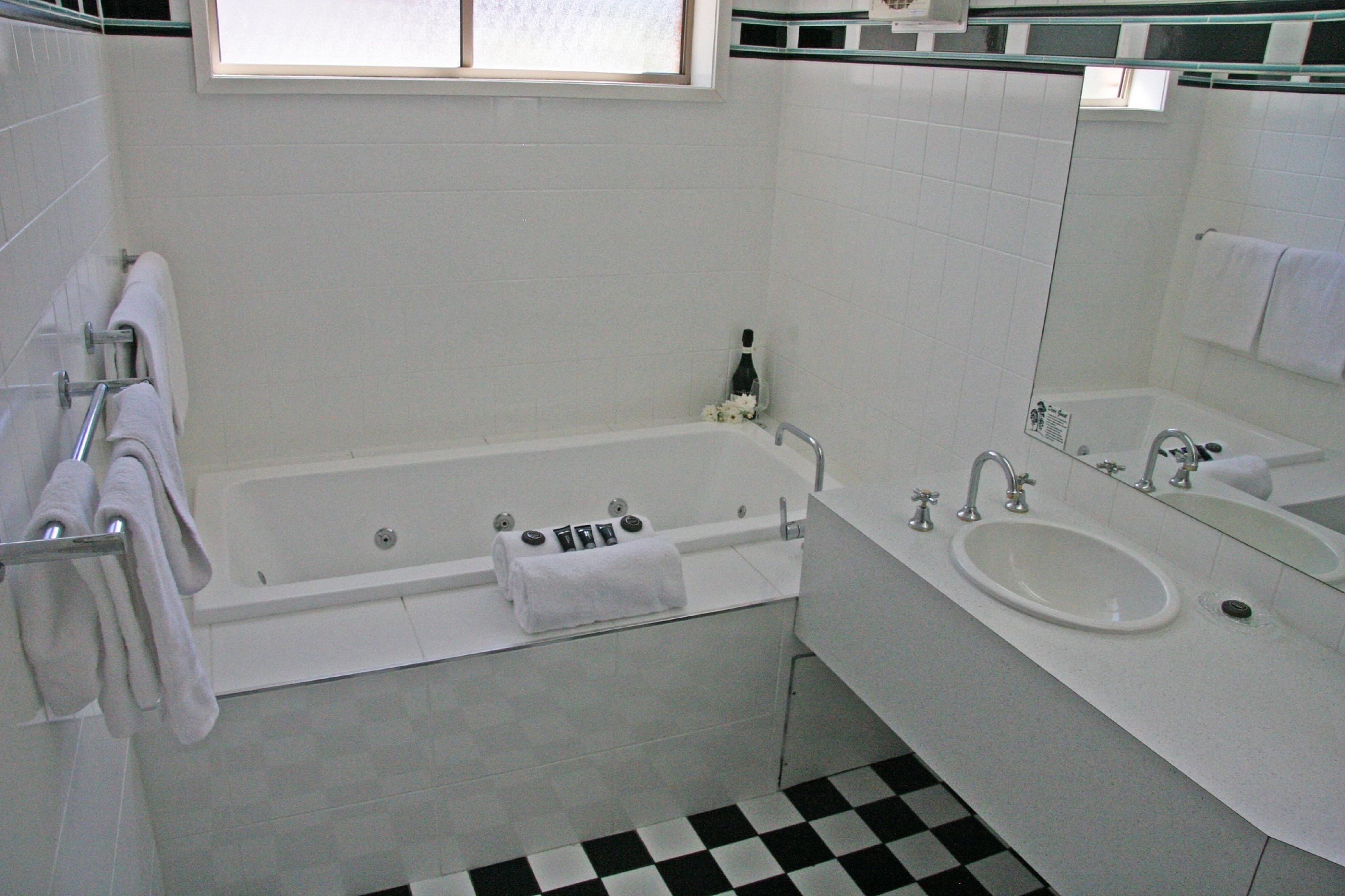 Un baño con bañera, lavamanos y espejo.