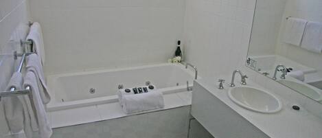 A bathroom with a bathtub, a sink, and a mirror.