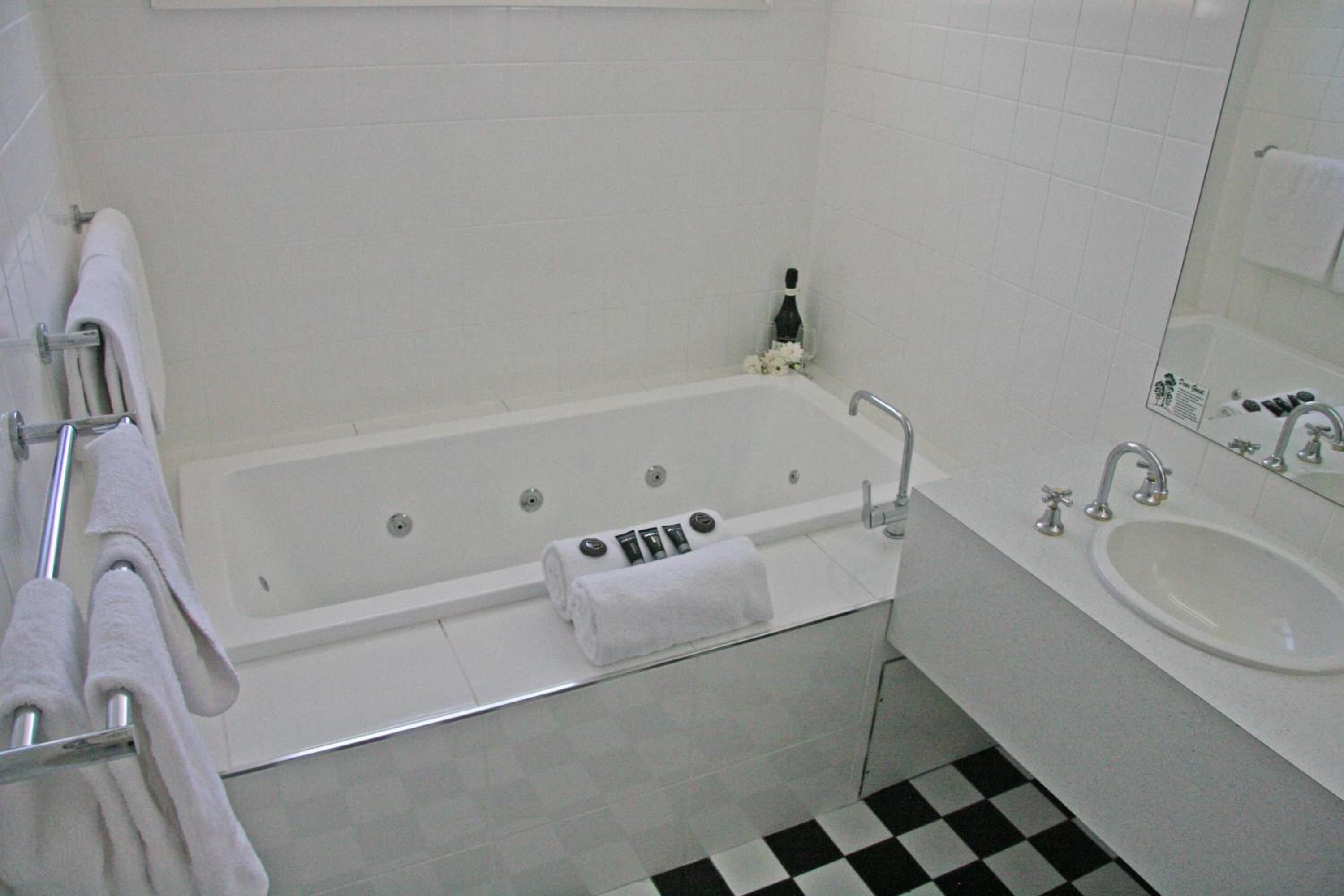 Un baño con bañera, lavamanos y espejo.
