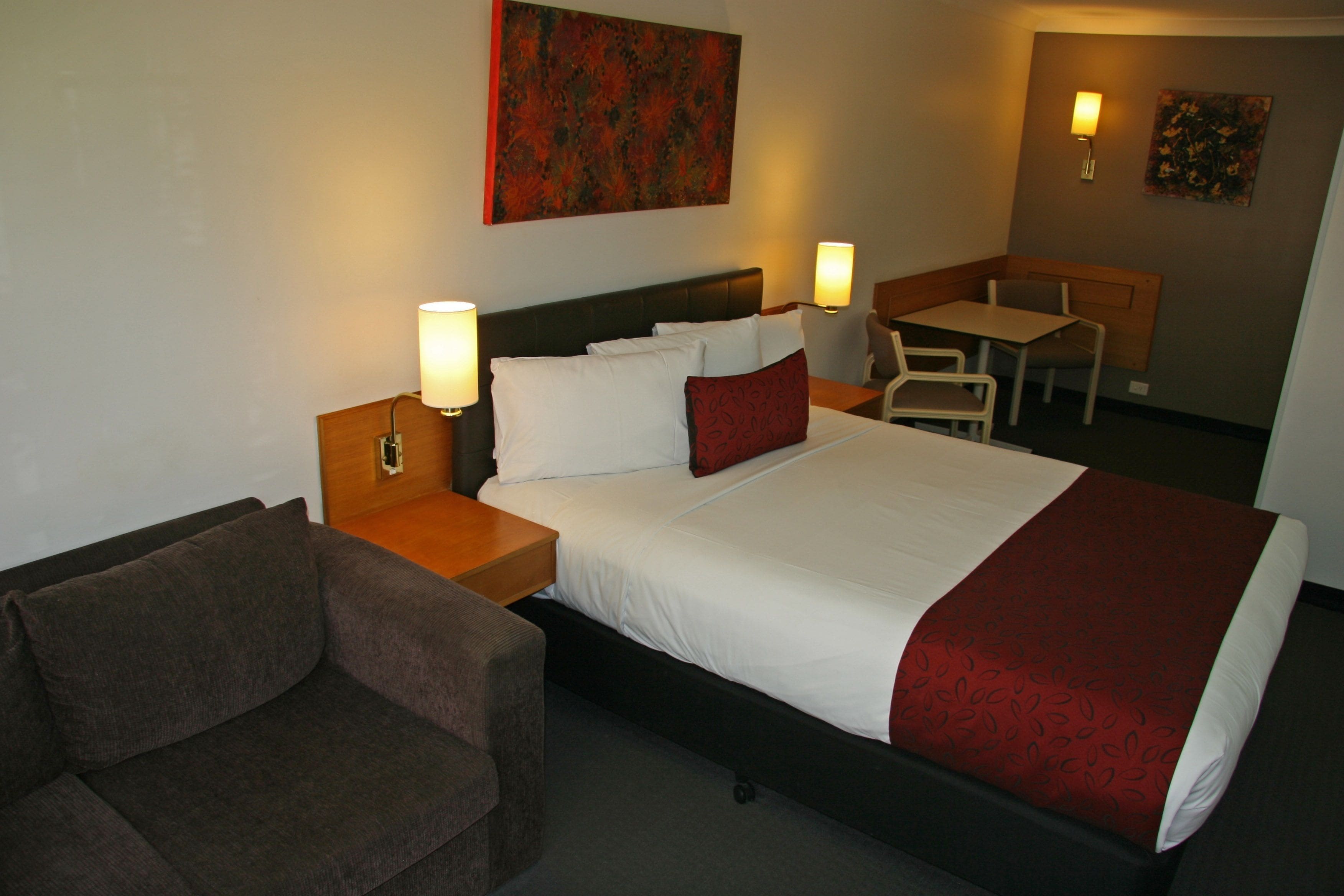 A hotel room with a bed, a desk, a chair, and a couch.