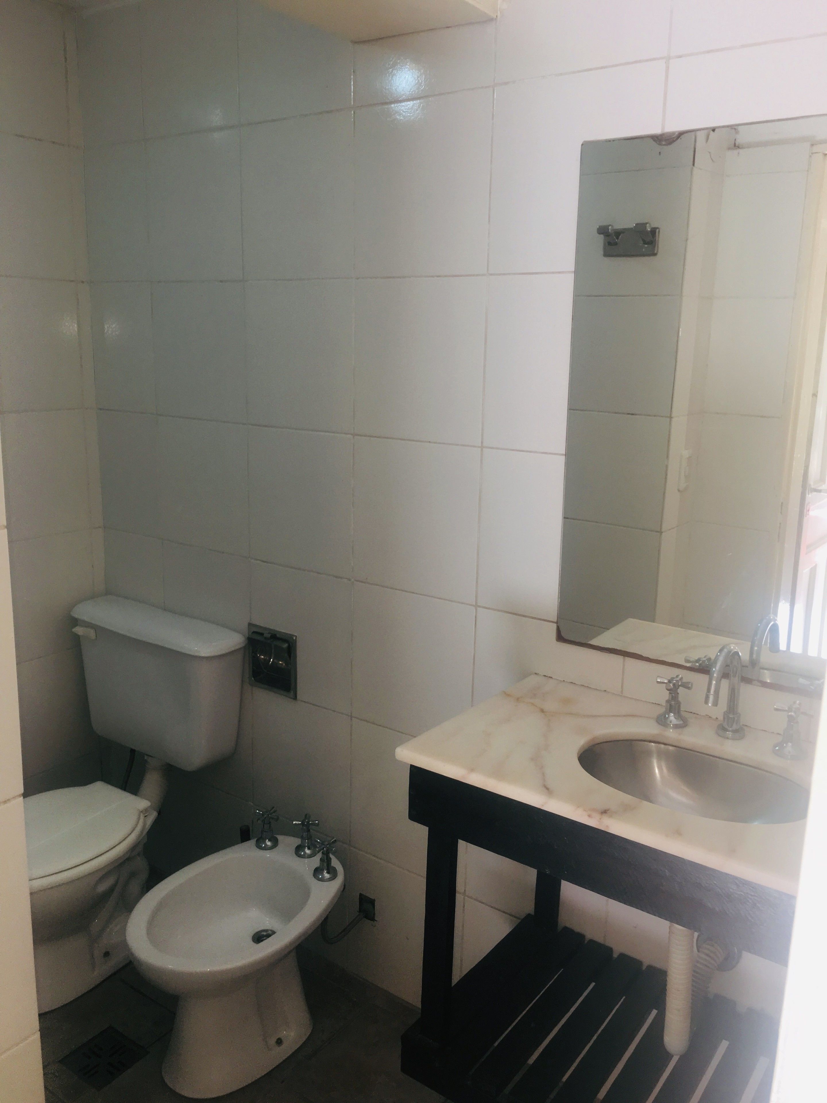 A bathroom with a toilet, bidet, sink, and mirror.
