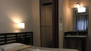 A hotel room with a bed, a bedside lamp, a mirror, and a bathroom with a sink and toilet. - Hotel Chipre (Buenos Aires)