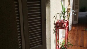 A wooden floor with a red plant stand holding several potted plants. - Hotel Chipre (Buenos Aires)