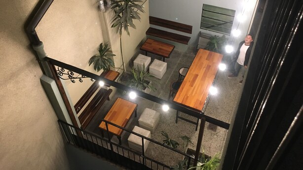 A multi-level indoor space with wooden tables and benches, potted plants, and a staircase. - Hotel Chipre (Buenos Aires)