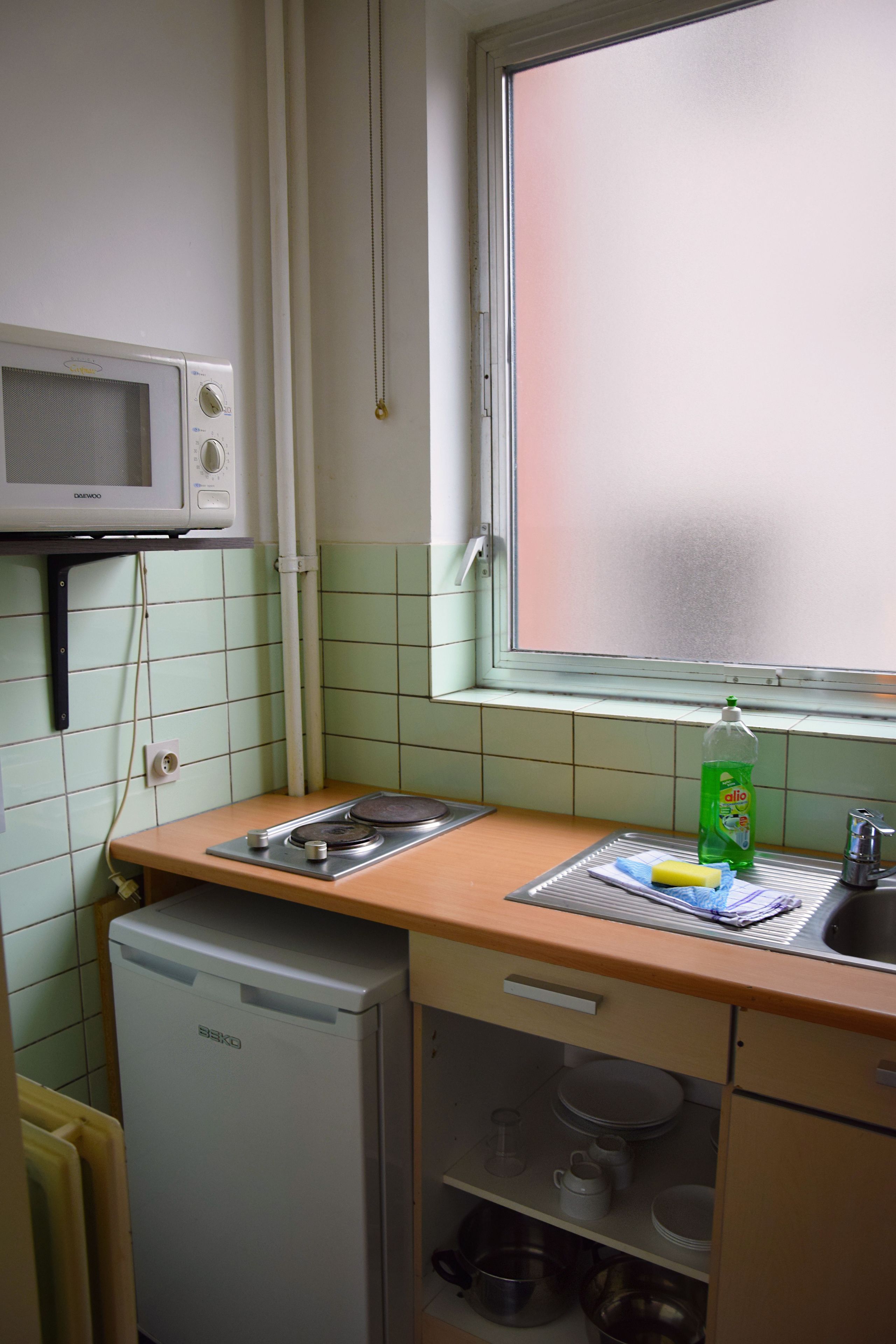 A compact kitchen with a microwave, sink, and a small refrigerator.