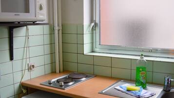 A compact kitchen with a microwave, sink, and a small refrigerator.