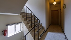 A staircase with a handrail, a fire extinguisher mounted on the wall, and a door at the end. - Budget Flats Antwerpen (Antwerp)