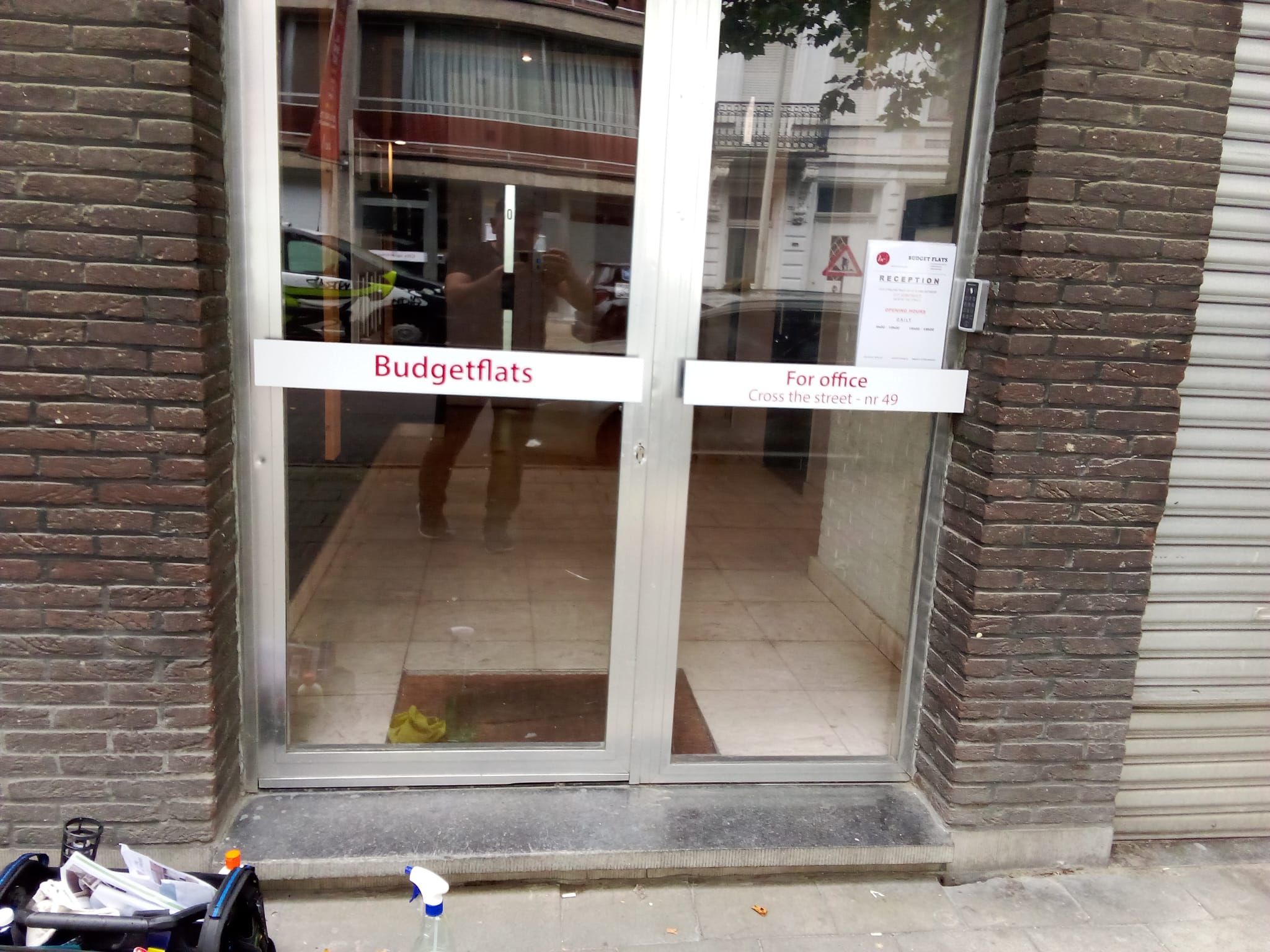 A building entrance with a glass door, a sign for 'Budgetflats' on the left, and a 'For office' sign on the right.