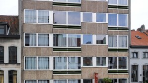 A multi-story building with a modern architectural style, featuring a mix of window types and a visible entrance. - Budget Flats Antwerpen (Antwerp)