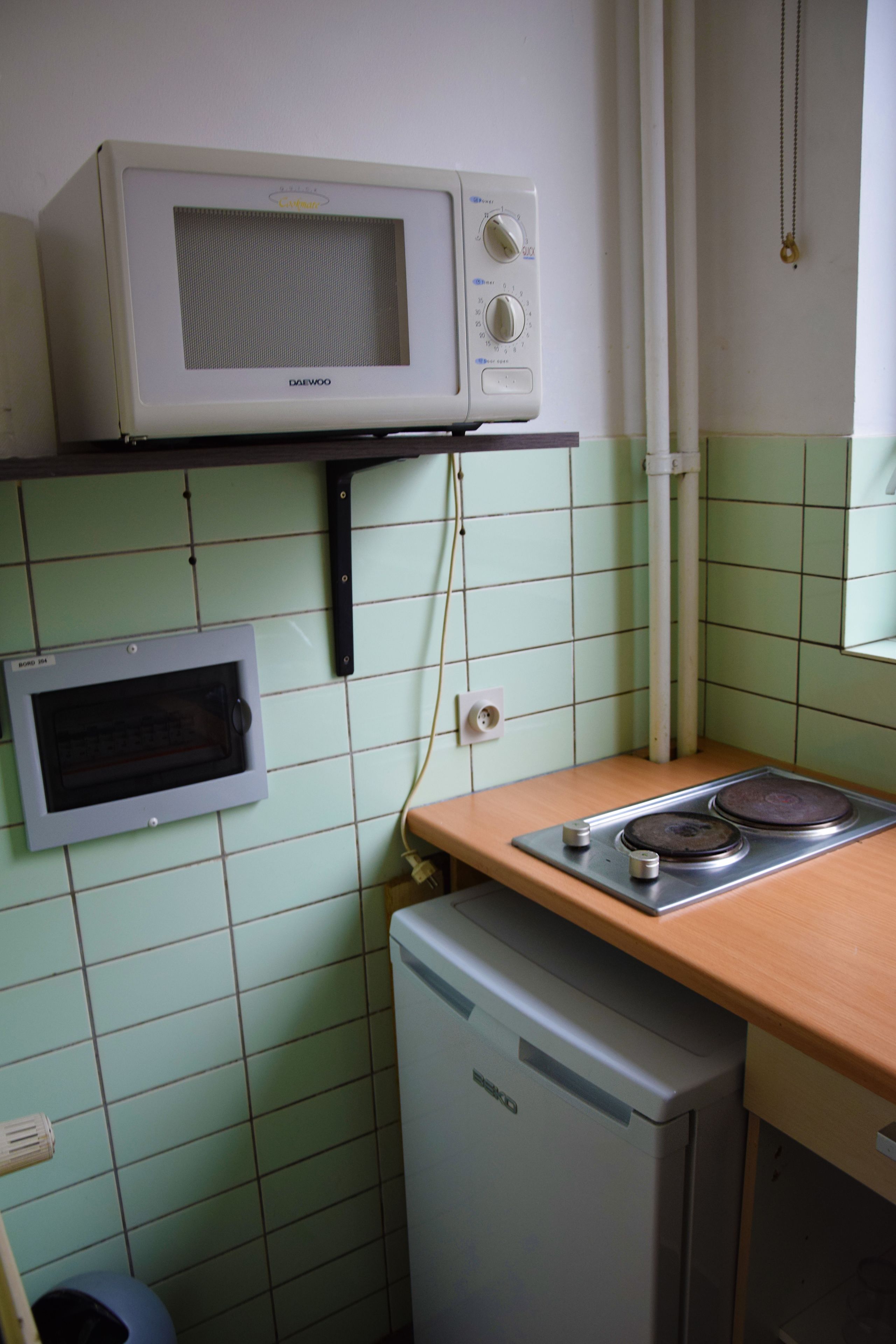 A compact kitchen with a microwave, a built-in oven, and a small refrigerator.