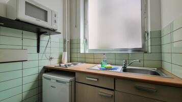 A compact kitchen with a microwave, sink, and a window above the counter.