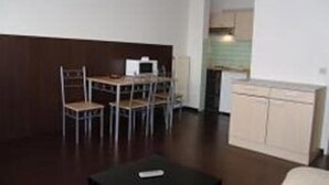 A compact living space with a dining area, kitchenette, and a small seating area. - Budget Flats Antwerpen (Antwerp)