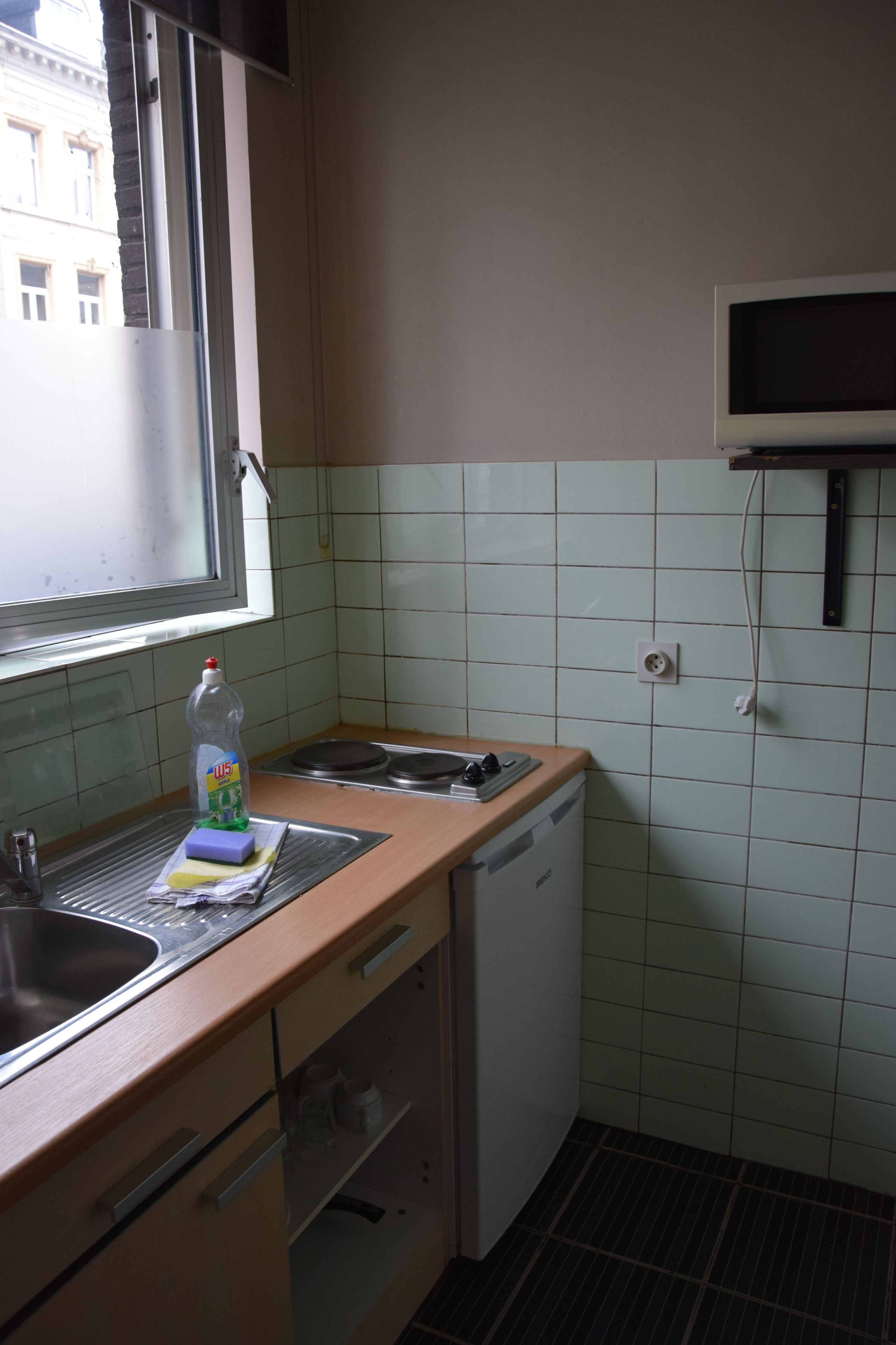 A small kitchen with a window, a microwave, a sink, and a dishwasher.