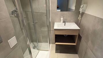 Un baño moderno con cabina de ducha de vidrio, inodoro y lavabo con espejo.