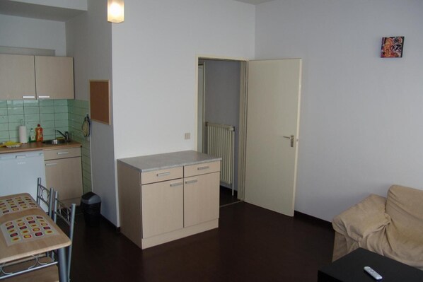 A compact living space with a kitchenette, a dining area, and a sofa.