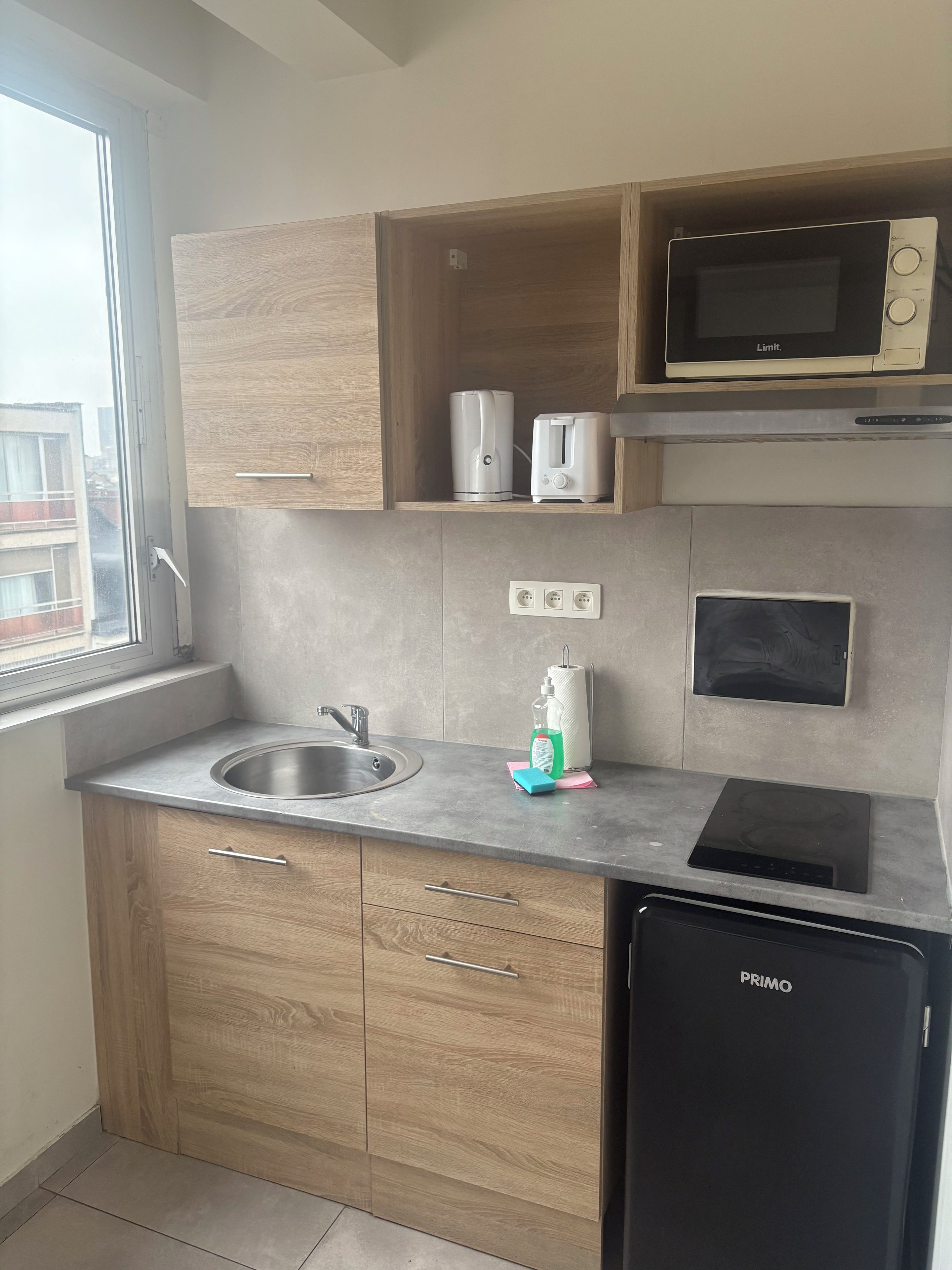A compact kitchen with a sink, a microwave, a toaster, and a built-in oven.