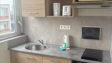 A compact kitchen with a sink, a microwave, a toaster, and a built-in oven.