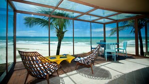 Un cuarto con paredes de vidrio que ofrece vista a la playa y al océano.