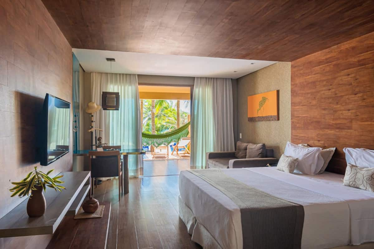 Habitación de hotel con una cama grande, un escritorio con silla, televisión y vista al exterior.