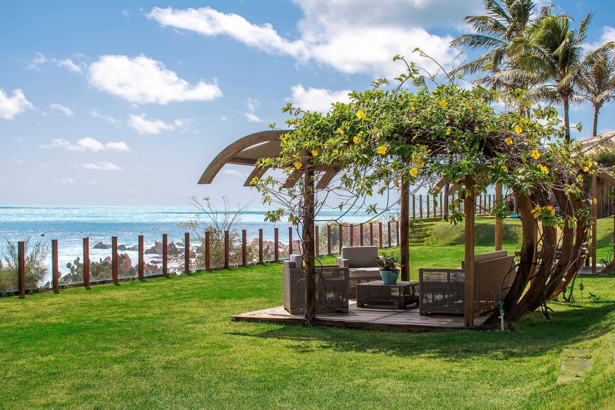 A patio with outdoor furniture, a pergola, and a view of the ocean.