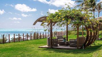 A patio with outdoor furniture, a pergola, and a view of the ocean.