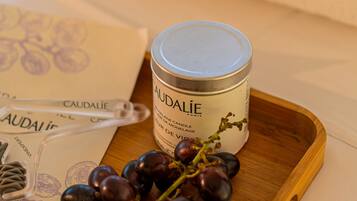 A candle, a bunch of grapes, and a pillow with the word "CAUDALIE" on it.
