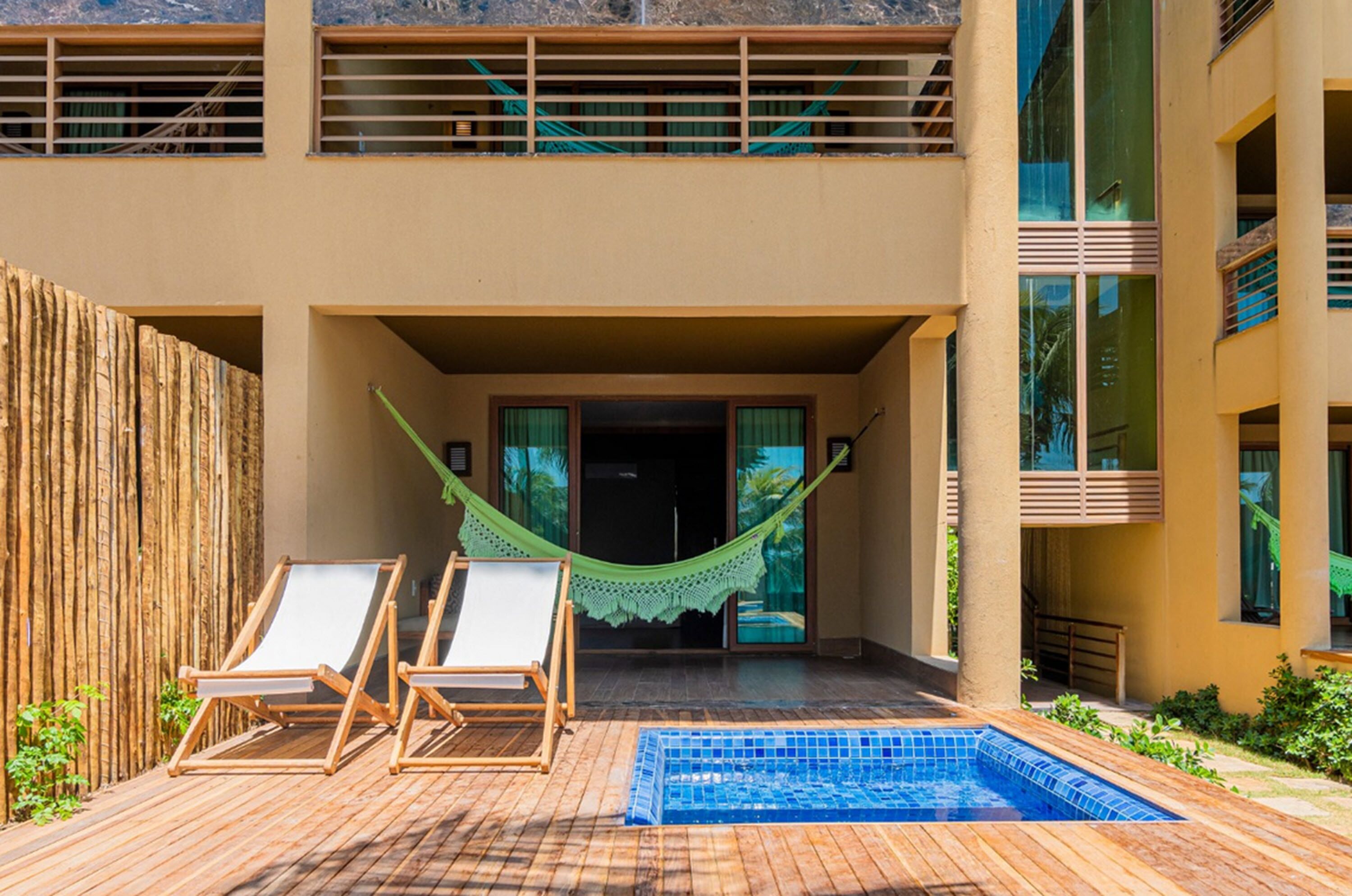 Un área de piscina con dos sillas de descanso y una hamaca.