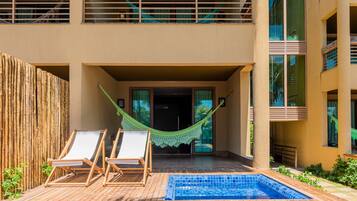 Un área de piscina con dos sillas de descanso y una hamaca.