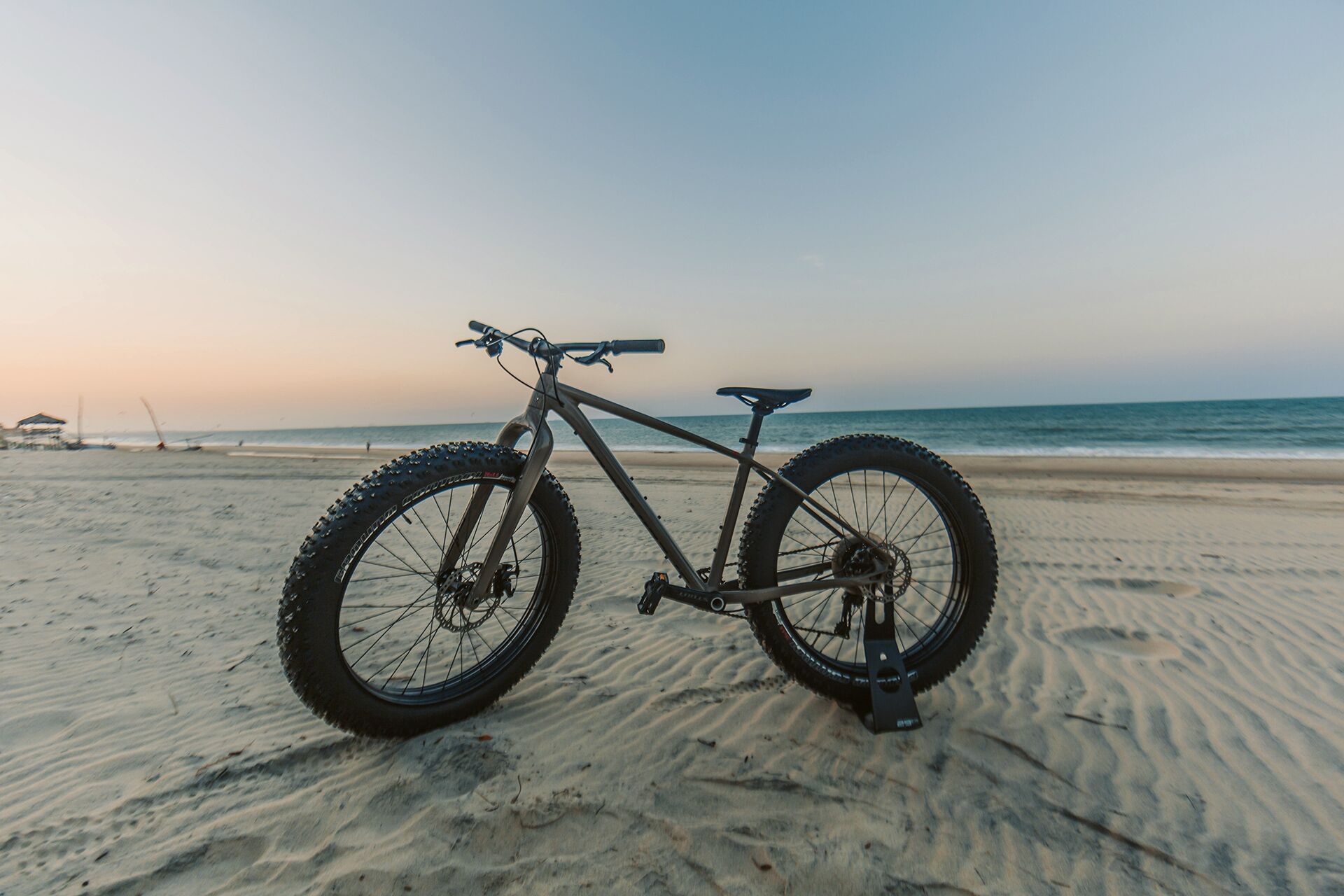 A mountain bike on a sandy beach with the ocean in the background.
