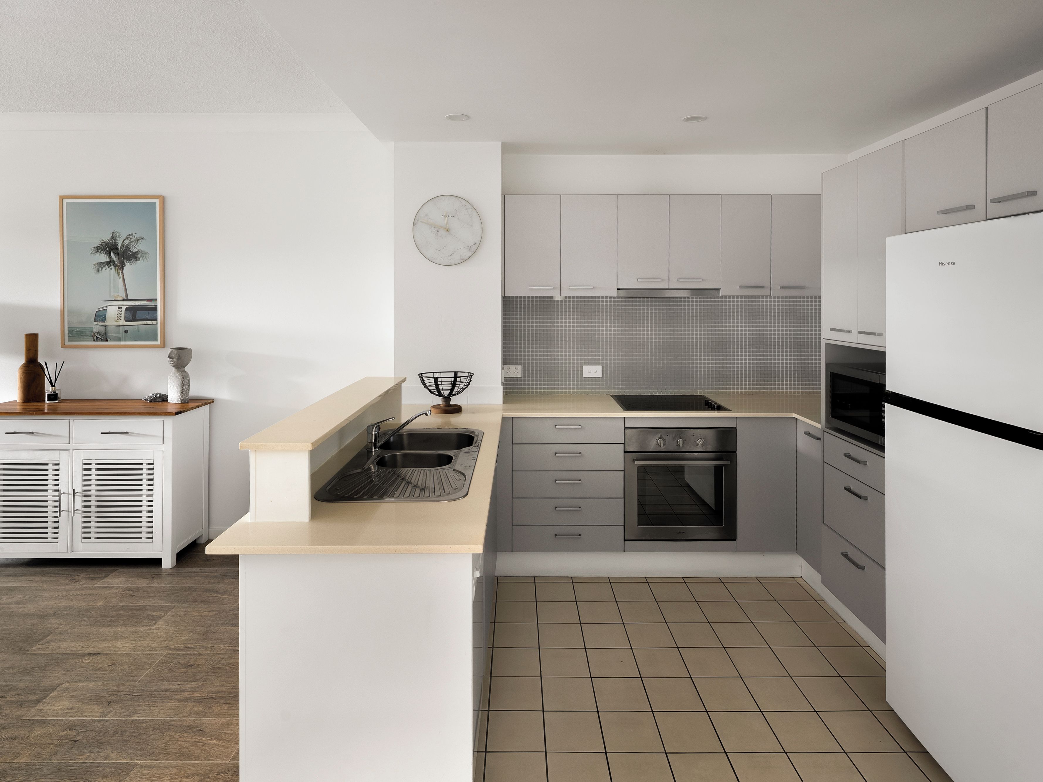 Une cuisine moderne avec des meubles blancs, un évier, une cuisinière et un four à micro-ondes.