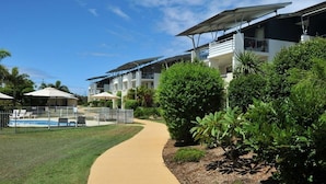Un hotel moderno con piscina, mobiliario exterior y jardines exuberantes.
