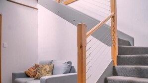 A modern interior with a grey sofa, wooden staircase, and a view of the upper floor. - Amble at Hahndorf (Hahndorf)