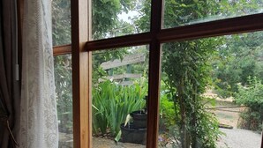 A room with a large window overlooking a garden. There is a table with plates and a cup. - Amble at Hahndorf (Hahndorf)